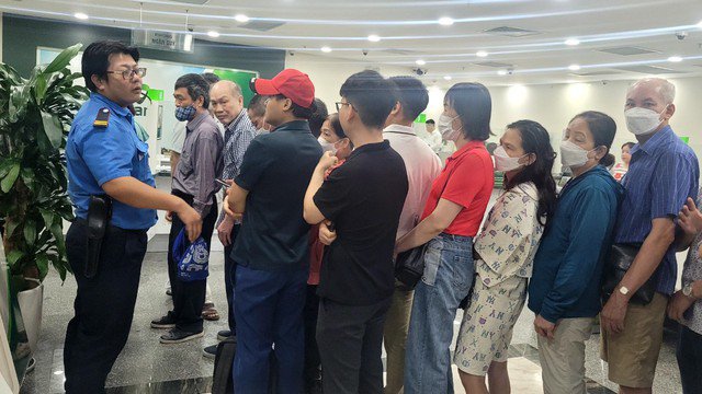 Nhân viên ngân hàng hướng dẫn khách xếp hàng, không chen lấn