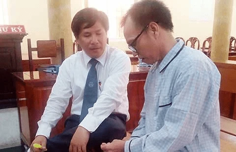 Bị cáo Nguyễn Tấn Khoa (phải) đang trao đổi với luật sư tại phiên tòa. Ảnh: LỆ TRINH