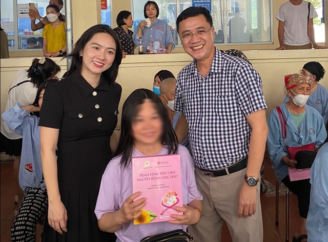 Ông Nguyễn Bá Tĩnh (bên phải) trao tặng tóc cho bệnh nhân ung thư. Ảnh: QNMTS