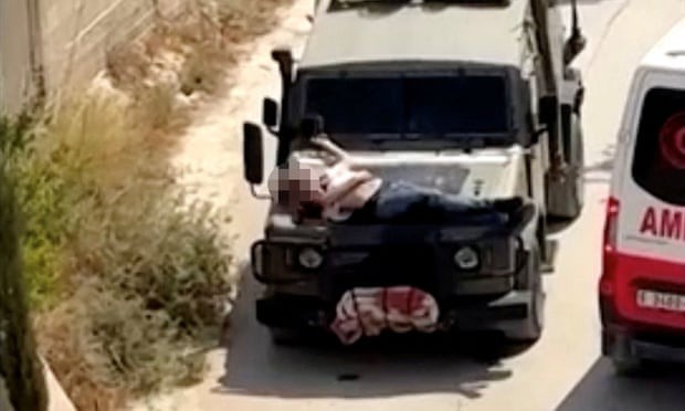 Ảnh chụp màn hình từ video binh sĩ Israel trói người đàn ông trên mui xe Jeep quân sự. Ảnh: Reuters
