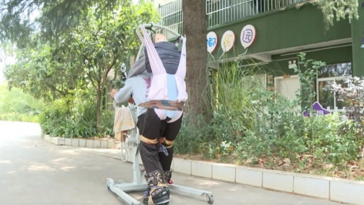 Bà Deng Guiying cõng con, giúp con tập luyện phục hồi sức khoẻ. Ảnh: SCMP