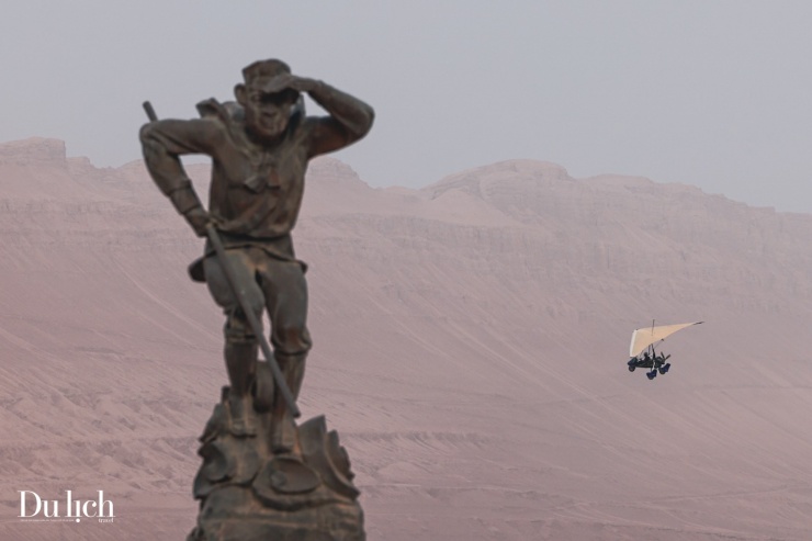 Hình ảnh chiếc dù lượn bay ngang tượng Tôn Ngộ Không trong khung cảnh hùng vĩ của Hỏa Diệm Sơn.