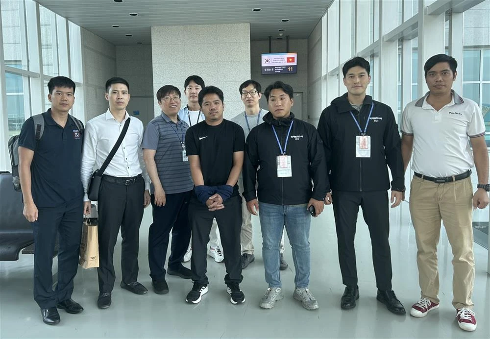 Interpol Hàn Quốc bàn giao cho Interpol Việt Nam bị can Nguyễn Văn Tấn (che hai tay đứng giữa) để dẫn giải từ Hàn Quốc về Việt Nam.Ảnh CA