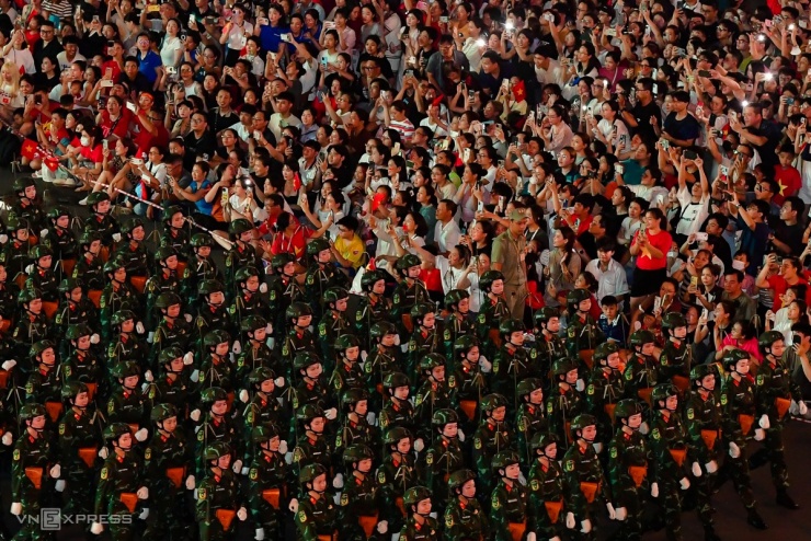 Khi đoàn diễu binh đi qua, người dân ngồi chật kín hai bên đường hò reo, cổ động, dùng điện thoại ghi lại khoảnh khắc.