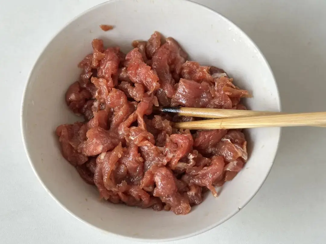 Thái thịt bò thành lát mỏng, ướp với 1 muỗng nước tương, 1 muỗng dầu hào, 2 muỗng bột bắp, ít tiêu trắng, bột gừng và một chút baking soda. Trộn đều rồi thêm một ít dầu ăn, để thịt nghỉ trong lúc chuẩn bị các nguyên liệu khác.