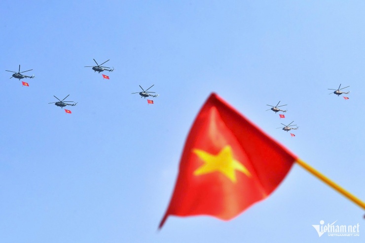 Biên đội trực thăng mang theo cờ Đảng và cờ Tổ Quốc bay trên bầu trời. Người dân ở dưới phấn khích vẫy cờ, reo hò, dùng điện thoại ghi lại những hình ảnh đáng nhớ trong ngày đại lễ 30/4.
