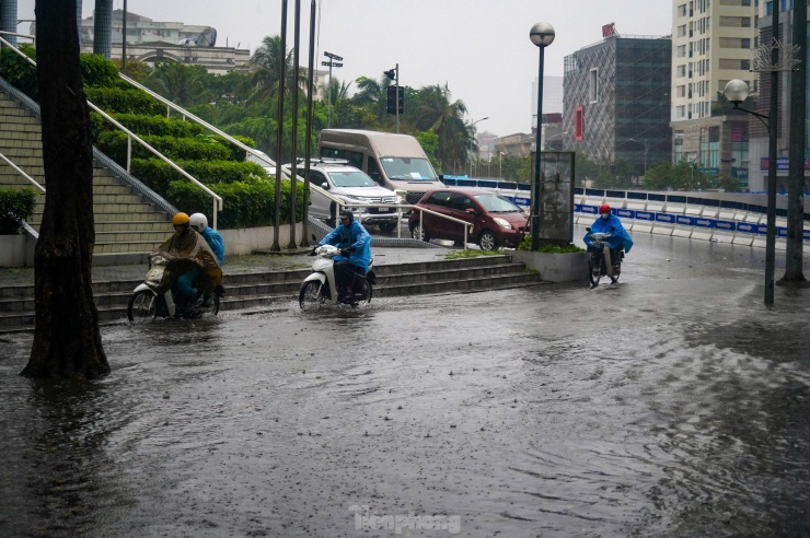 Nhiều xe máy phải 'rồng rắn' leo lên vỉa hè để thoát khỏi chỗ ngập sâu.