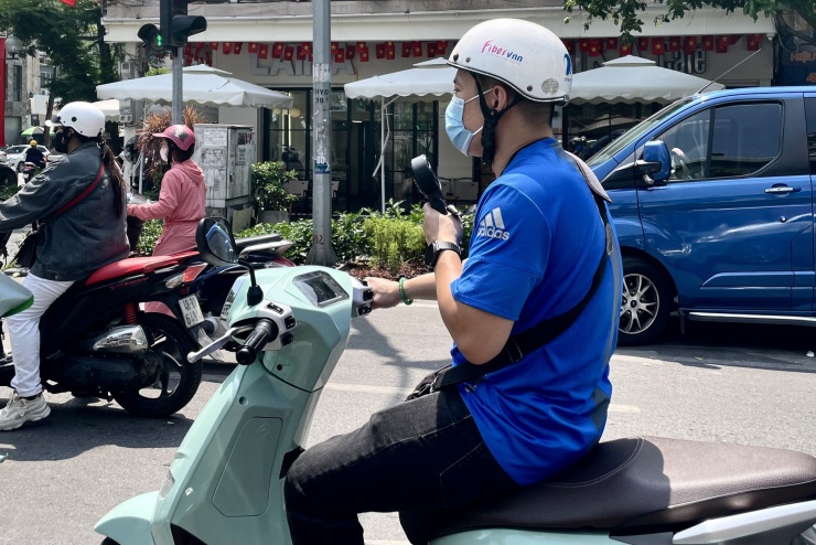 Người đàn ông vừa đi đường vừa dùng quạt tay để đối phó với cái nóng lên đến 36 độ C.