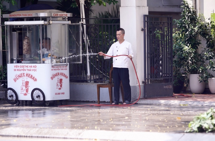 Người đàn ông tưới nước để giảm nhiệt độ vỉa hè.