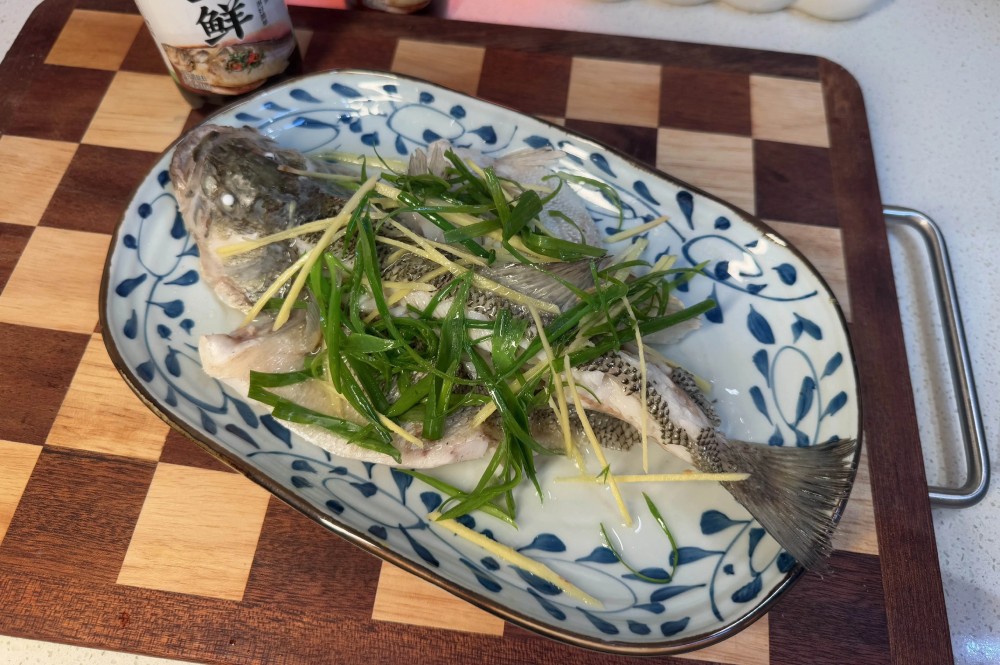 Lấy cá ra, bỏ nước hấp tanh đi. Rải hành và gừng thái sợi lên thân cá, đun nóng một thìa dầu rồi chan lên để dậy mùi thơm.