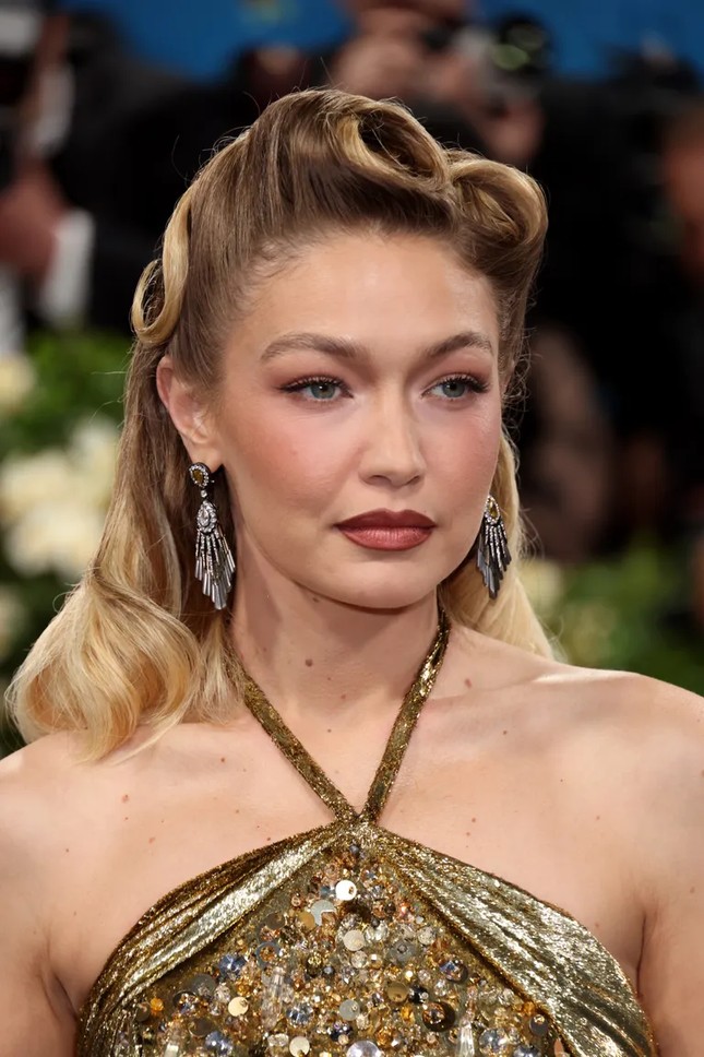Gigi Hadid tạo kiểu tóc xoăn pin-up theo phong cách thập niên 40, kết hợp với trang điểm tông nâu trầm, tạo nên vẻ đẹp đầy nữ tính.