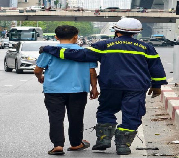 Lực lượng cứu hộ giải cứu thành công nam thanh niên ngồi trên lan can cầu vượt. Ảnh CAHN.