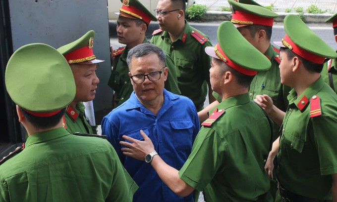 Bị cáo Đoàn Văn Huấn, Chủ tịch Công ty Thái Dương, bị áp giải rời xe thùng. Ảnh: Phạm Dự