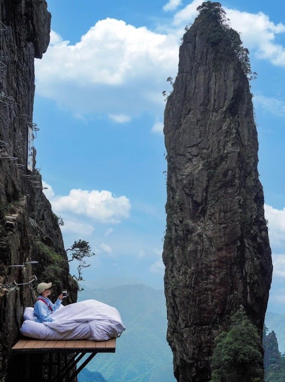 Du khách check in trên chiếc giường ngủ trên vách núi cao 1.600 m. Ảnh: Xiaohongshu