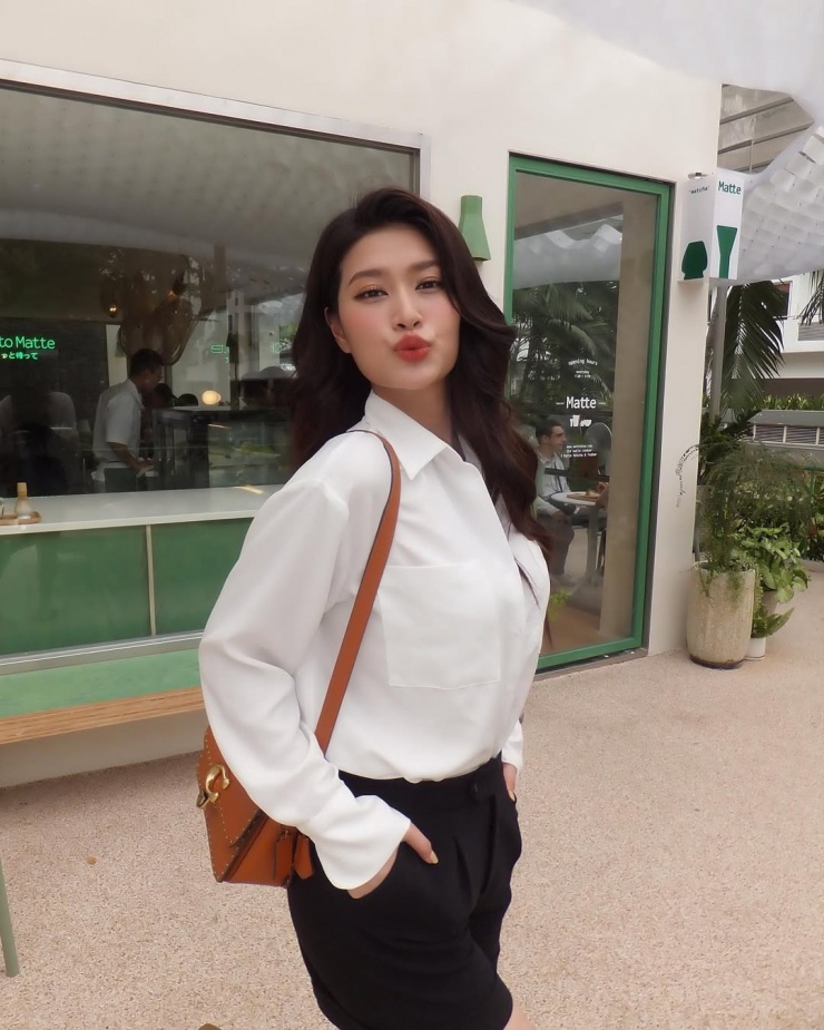 Cô thể hiện phong cách doanh nhân thành đạt qua bộ trang phục công sở gồm sơ mi trắng, quần shorts đen, nhấn bằng túi Coach nâu da bò. Ngoài túi hiệu, cô còn sắm dép Hermes, thắt lưng Celine.