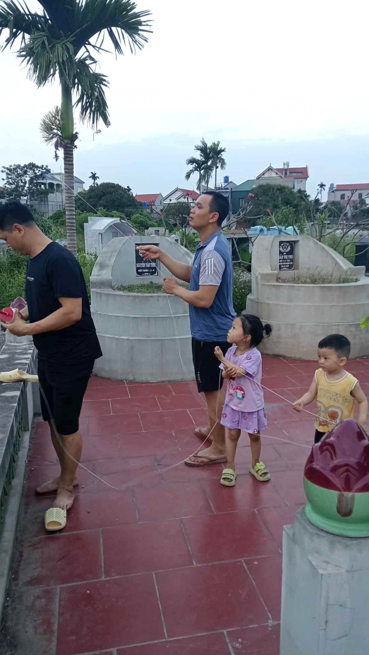 Chồng (áo đen) và con gái chị Hà thường ghé nghĩa trang vào chiều hè để thả diều, vừa thư giãn, vừa hít hà không khí trong lành. Ảnh: Hachi Hachi