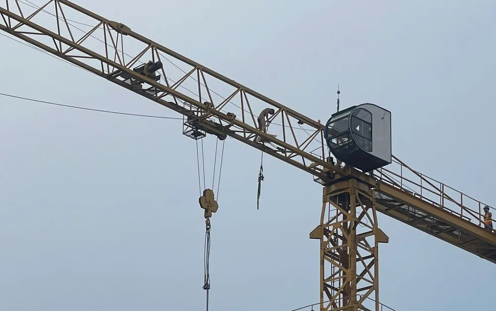 Người đàn ông không mặc quần áo leo lên cần cẩu công trình.