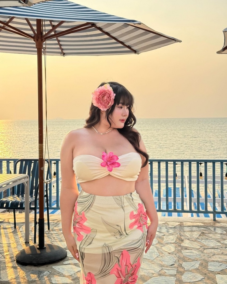 Điểm nhấn là đóa hoa cài tóc và bông hoa nổi bật giữa ngực, vừa nữ tính vừa tôn lên thần thái quyến rũ.