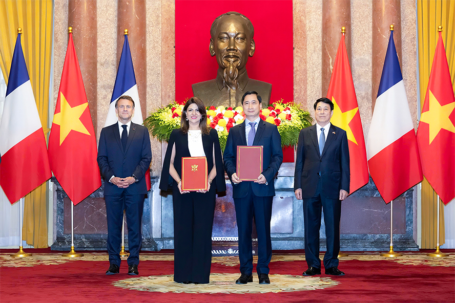 Ông Ngô Chí Dũng, Tổng Giám đốc kiêm Chủ tịch HĐQT Công ty Vắc xin Việt Nam (VNVC) và bà Zainab Sadat Qayyum, Phó Chủ tịch Sanofi vùng Đông Nam Á - Ấn Độ trao văn kiện thỏa thuận hợp tác chuyển giao công nghệ sản xuất vắc xin của Sanofi tại Nhà máy Vắc xin và Sinh phẩm VNVC trước sự chứng kiến của Chủ tịch nước Lương Cường và Tổng thống Pháp Emmanuel Macron. Ảnh: Hải Nam
