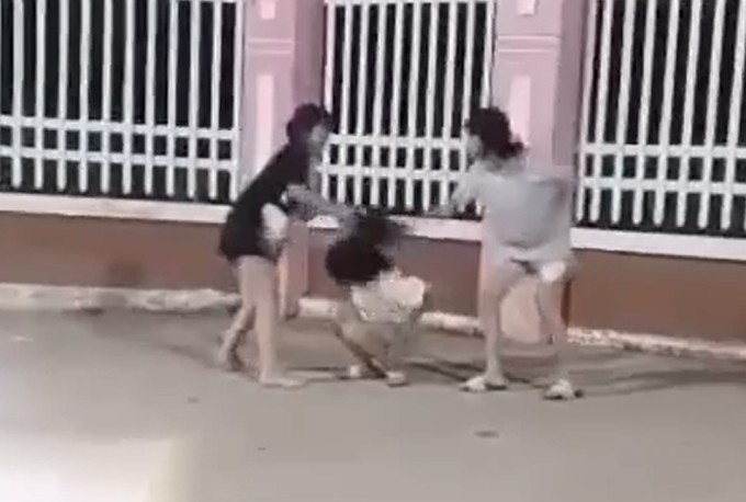 Nữ sinh lớp 6 tại TP Long Xuyên bị hai bạn khác đánh bằng nón bảo hiểm. Ảnh cắt từ video.