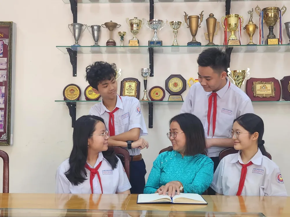 Cô Hoàng Thị Hoài Thương cùng với học trò của mình tại phòng truyền thống của trường. Ảnh: NGUYỄN QUYÊN