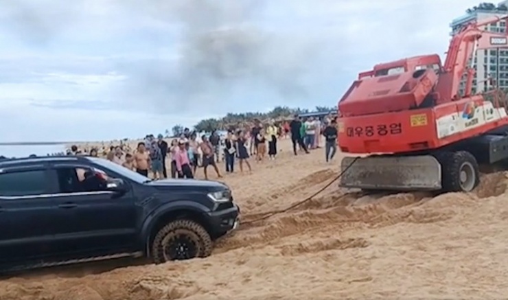Sau một hồi chạy ngông nghênh trên bãi biển, lái xe đã phải thuê phương tiện cơ giới chuyên dụng cẩu kéo xe ô tô bán tải ra khỏi hiện trường sa lầy do lún cát. (Ảnh cắt từ clip).