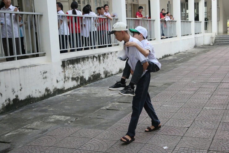Trung Dũng cõng Tuấn Anh vào phòng thi tại điểm thi Trường THPT Chuyên Hạ Long. Ảnh: Minh Hà