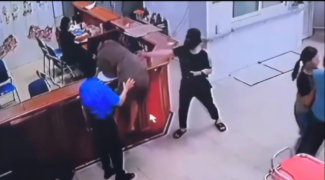 Hình ảnh người đàn ông chồm qua quầy làm thủ tục để hành hùng nhân viên y tế. Ảnh cắt từ clip.