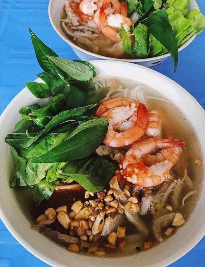 Thịt và tôm sau khi luộc sẽ được xếp lên trên bún tươi đã trụng nóng, thêm rau sống như giá, húng quế, xà lách, rồi chan nước dùng nóng lên. Hành phi vàng ruộm, vài lát ớt đỏ, chút mắm nguyên chất đi kèm sẽ làm dậy mùi và hoàn thiện món ăn. Ảnh MIA