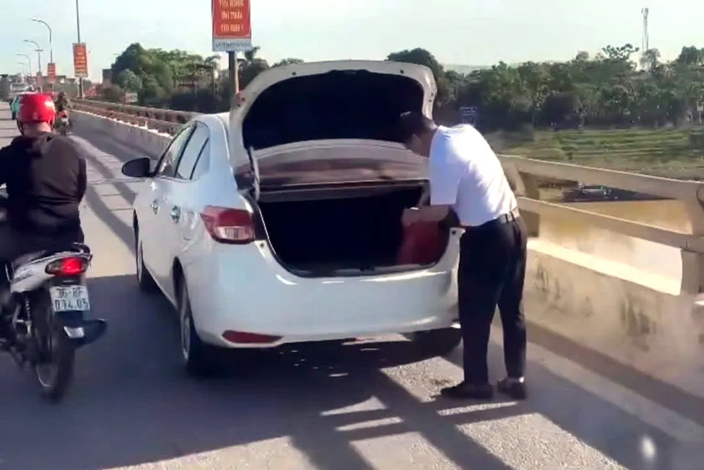 Hình ảnh người đàn ông đỗ xe trên cầu Vạn Hà xả rác xuống sông Chu.