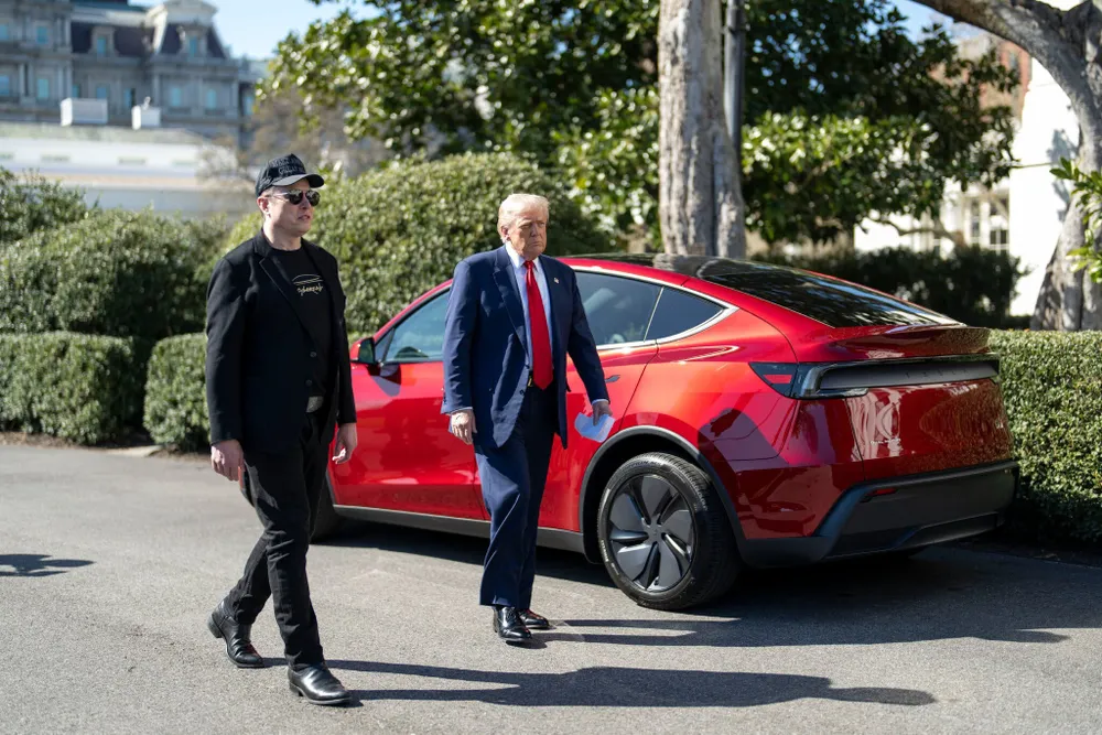 Tổng thống Mỹ Donald Trump (phải) và tỉ phú Elon Musk bên cạnh Tesla Model S màu đỏ trên bãi cỏ Nhà Trắng hồi tháng 3. Ảnh: THE NEW YORK TIMES