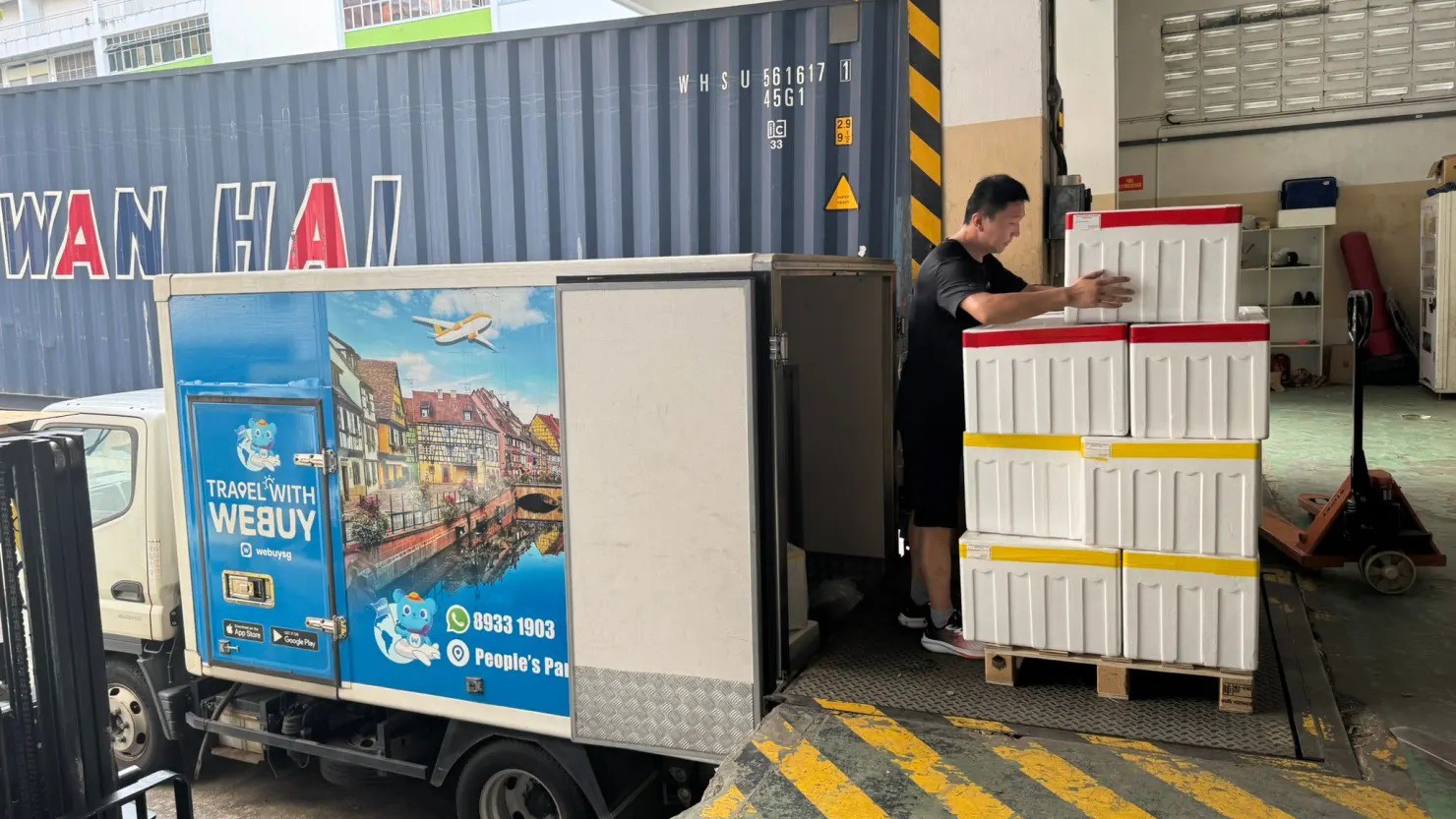 Nhân viên của Webuy, một nhà bán lẻ thực phẩm trực tuyến có trụ sở tại Singapore, đang dỡ các container chứa hàng hóa được vận chuyển từ Trung Quốc.