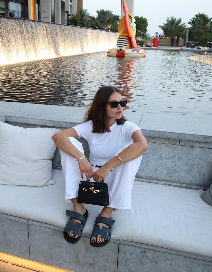 Áo phông và quần jeans trắng được tô điểm bằng phụ kiện tối màu gồm túi Kelly mini và sandals Hermes. Thylane chuộng túi và giày của hãng mốt này. Ngoài ra, cô còn có một số túi của Miu Miu và Chanel.