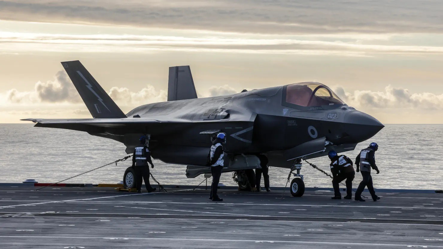 Các phi hành đoàn đi về phía máy bay chiến đấu F-35B Lightning của Hải quân Hoàng gia Anh để chuẩn bị cất cánh từ boong tàu sân bay HMS Prince Of Wales của Anh