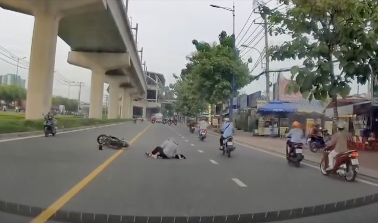 Cú đạp xe khá nguy hiểm, khiến người và xe té ra giữa đường, trước mặt ô tô đang lưu thông. Ảnh: Cắt từ clip