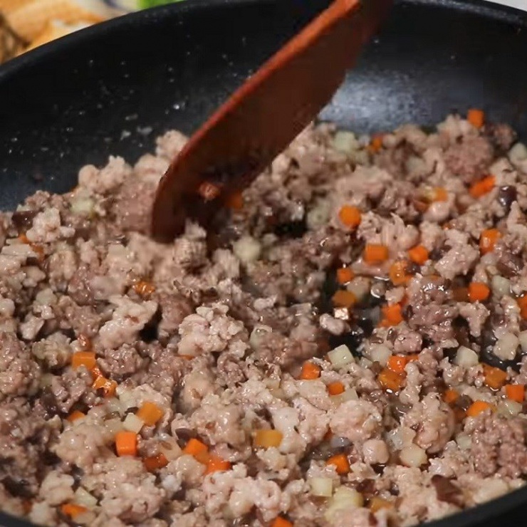 Sau đó, cho thịt heo xay và thịt bò xay vào xào khoảng 5 phút cho chín. Nêm vào thịt 1 muỗng canh nước mắm, 1/4 muỗng cà phê muối, 1 muỗng cà phê hạt nêm. Thêm củ sắn, cà rốt, nấm mèo vào xào khoảng 5 phút cho chín, nêm nếm cho vừa ăn, tắt bếp.