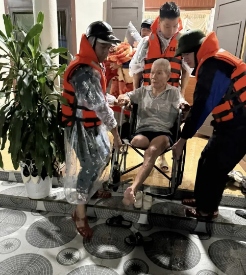 Lực lượng chức năng hỗ trợ sơ tán người già đến nơi cao để tránh ngập lụt