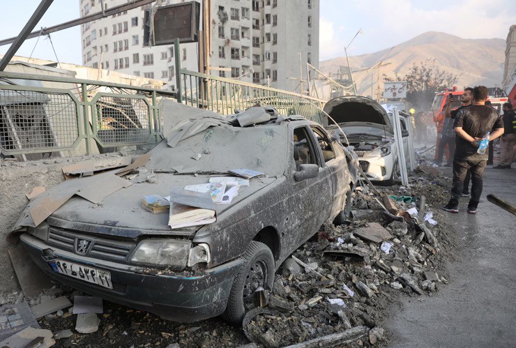 Người dân Iran tập trung quanh nơi những chiếc xe bị hư hại sau đòn không kích từ Israel. Ảnh: Reuters.