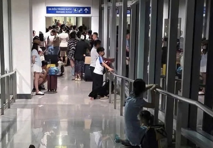 Hành khách phải ngồi, đứng trong hành lang ống lồng do cánh cửa dẫn vào nhà ga bị khóa (Ảnh: NVCC).