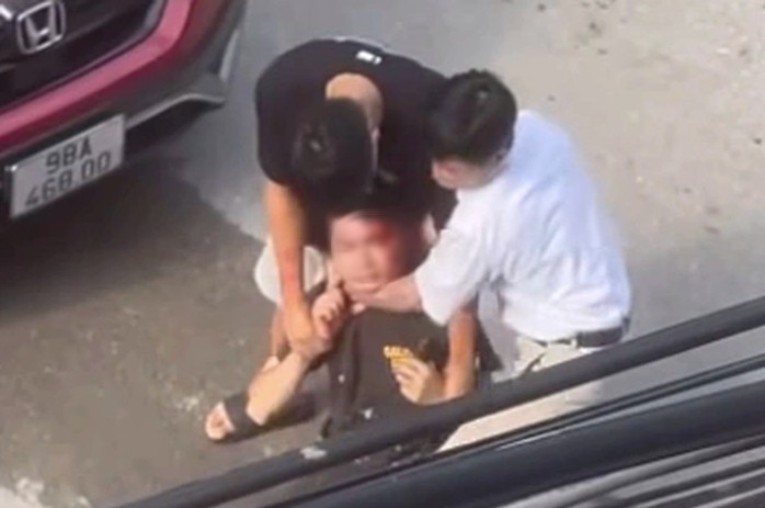 Nam thanh niên bị 2 người đi xe ô tô khống chế. Ảnh cắt từ clip
