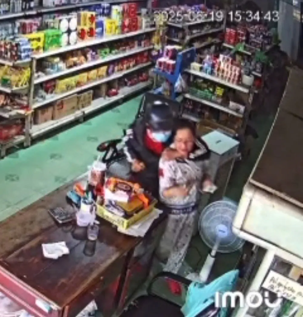 Nữ chủ tiệm tạp hoá bị hung thủ dùng dao khống chế. Ảnh: Cắt từ clip.
