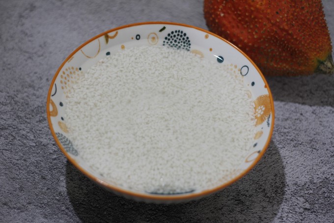 Gạo nếp đãi sạch cho tới khi nước trong, ngâm với nước lạnh 6 - 8 giờ (nếu muốn nhanh hơn thì ngâm nước ấm 4 giờ). Sau đó, đổ ra rá dội lại nước lã, để cho ráo nước, cho 1 thìa cà phê muối tinh vào xóc nhẹ/hoặc trộn nhẹ tay (tránh làm hạt nếp bị gãy nát).