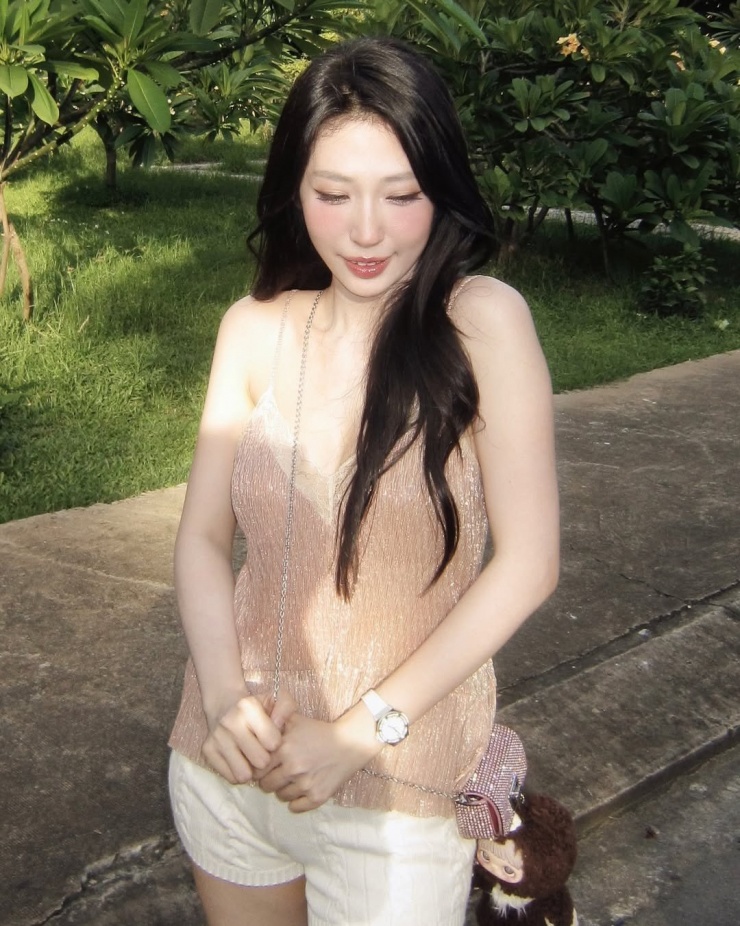 Cô nhắm mắt, đón lấy ánh nắng dịu nhẹ sau cơn mưa, mái tóc đen dài bồng bềnh xõa tự nhiên, tạo nên một khung cảnh đầy thơ mộng và an yên.