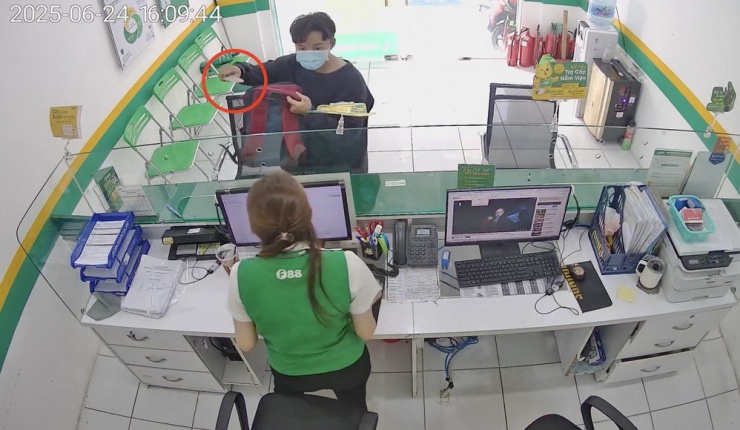 Tên cướp dùng dao uy hiếp nữ nhân viên cửa hàng. Ảnh: Cắt từ clip.