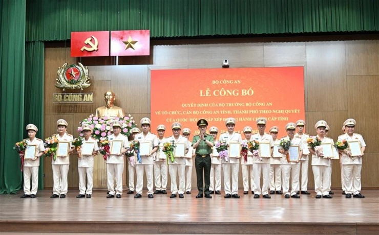 Bộ trưởng Lương Tam Quang trao quyết định và tặng hoa chúc mừng 23 giám đốc công an địa phương sau sáp nhập. Ảnh: Bộ Công an