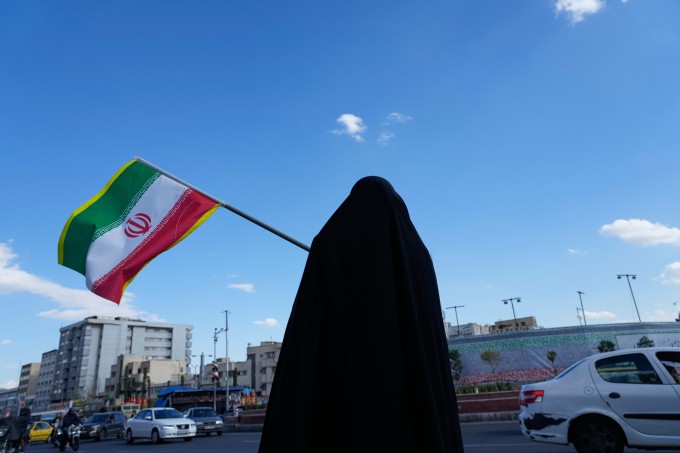 Người phụ nữ cầm cờ Iran trên đường phố ở Tehran hôm 30/3. Ảnh: AP