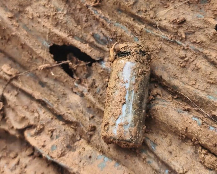 Di vật có lọ thủy tinh nghi chứa thông tin chôn cùng hài cốt liệt sĩ. Ảnh: Duy Đông