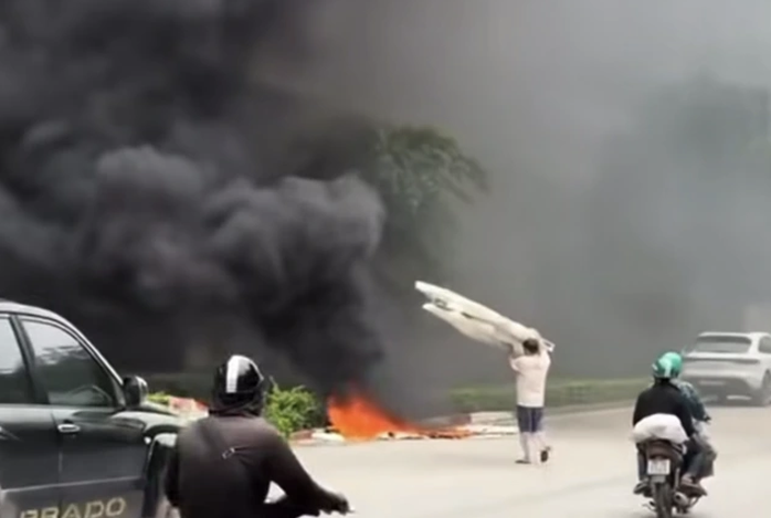 Người đàn ông mang những tấm xốp lớn vứt vào đống lửa đang cháy. Ảnh chụp màn hình