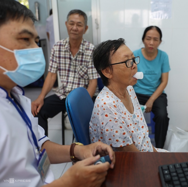 Tại phòng đo hô hấp ký, bà Tú Khánh được bác sĩ thăm dò chức năng phổi không xâm lấn. Nhà ở gần trạm y tế, cụ bà 72 tuổi tự đạp xe tới để được khám bệnh miễn phí.
