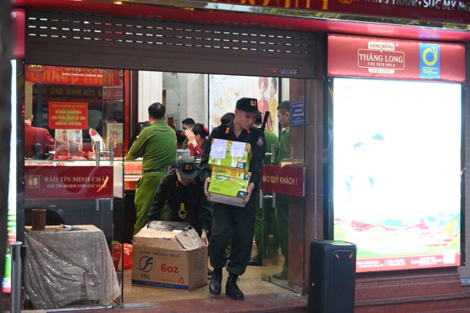 Công an bê tài liệu ra khỏi Bảo Tín Minh Châu ở cơ sở 29 Trần Nhân Tông, chiều 25/3. Ảnh: Linh Đan